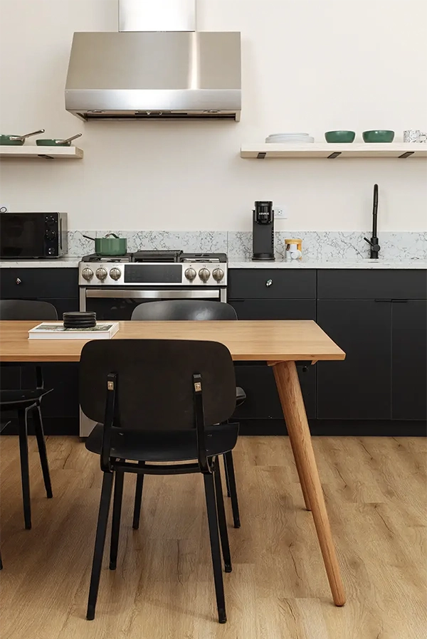 Wooden dining table with a black chair in front of a kitchen counter