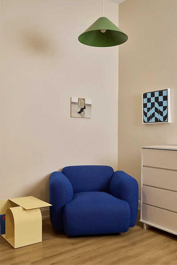 Corner of a room with a blue armchair and a withe chest of drawers