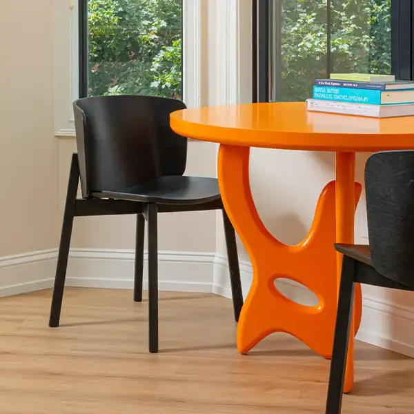 Black table next to an orange chair with books on it