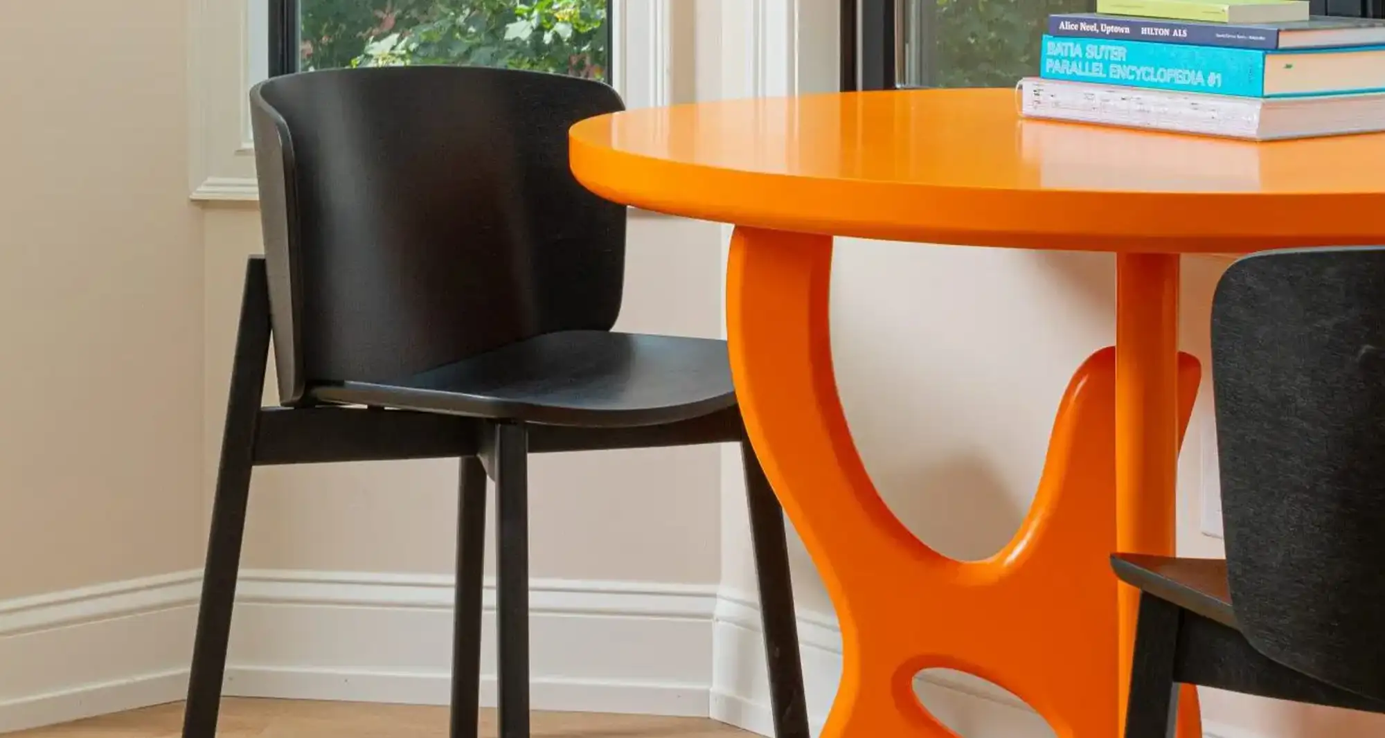 Black table next to an orange chair with books on it