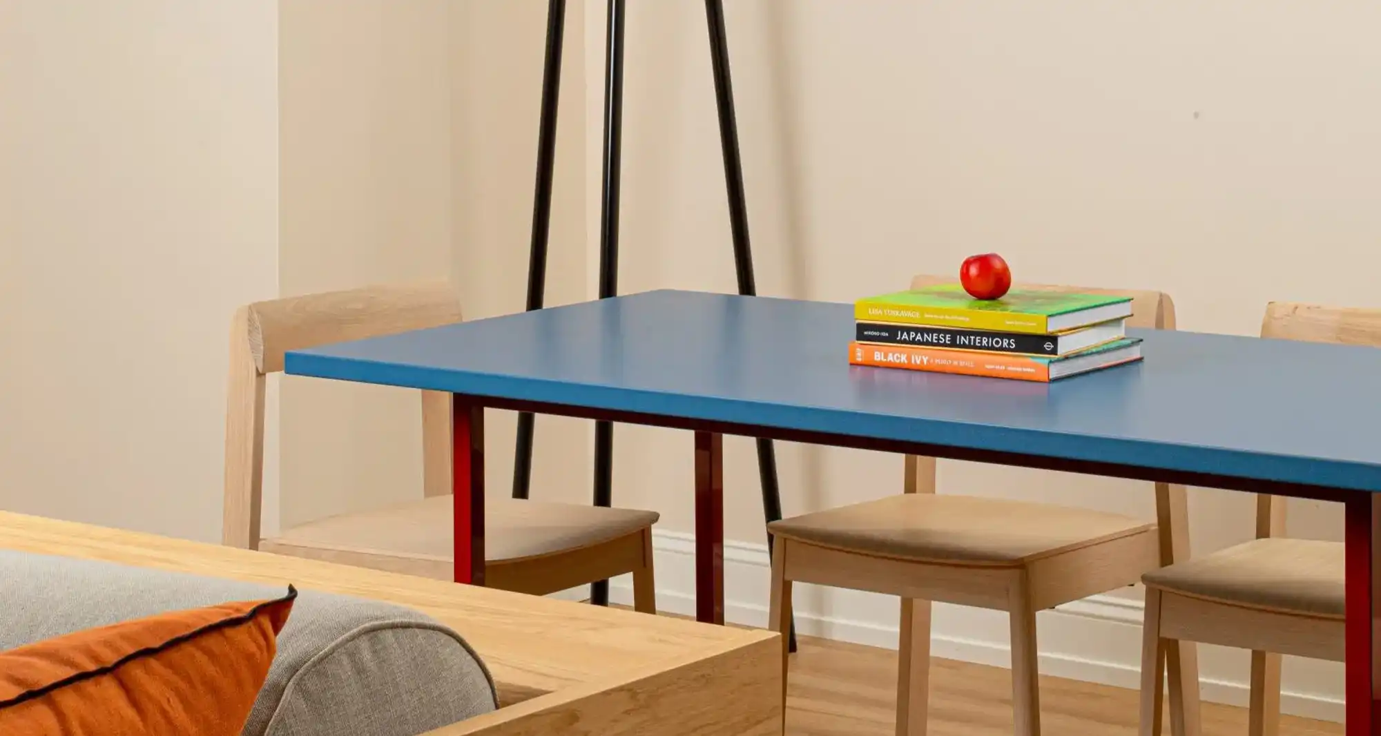 blue dining table with books on it, an apple and a floating lamp