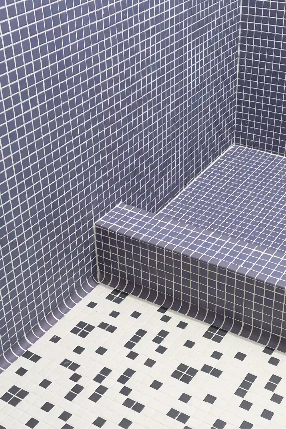 Modern bathroom design with dark blue mosaic shower tiles and patterned black-and-white floor tiles