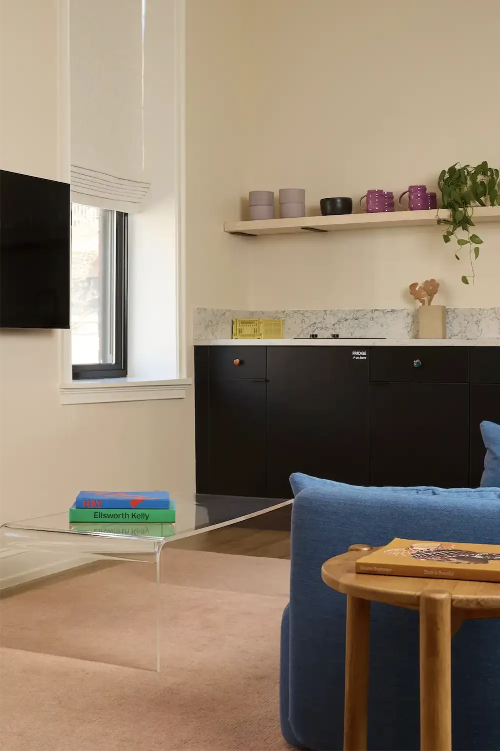 Corner of a blue sofa in front of a tv with a glass and stone coffee table
