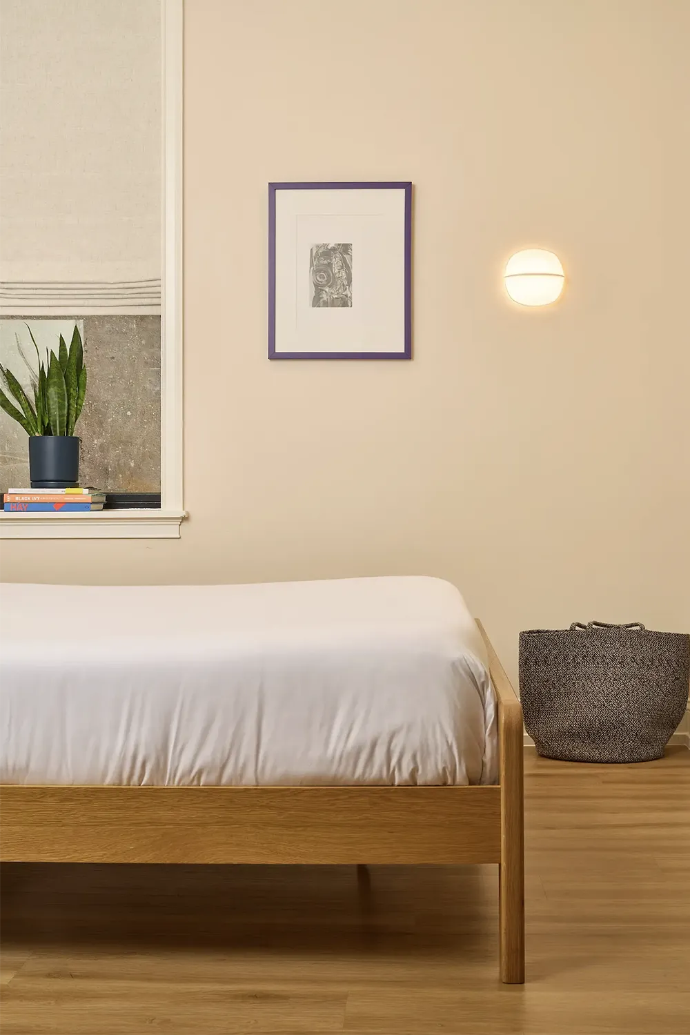 Beige room with a double wood foot bed with white sheets, a purple picture frame