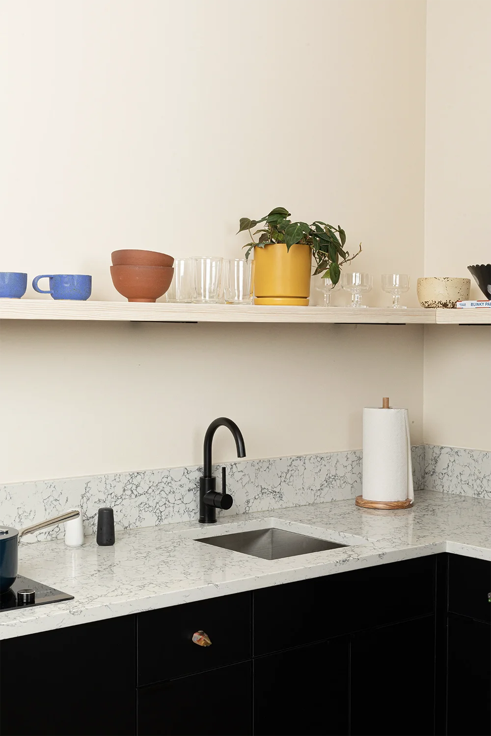 marble kitchen corner countertop with a shelf on top with mugs, bowls and glasses