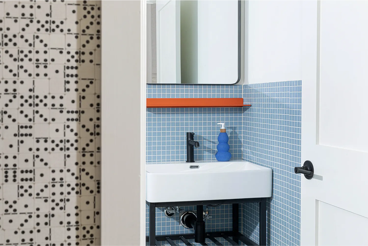 View of a blue tiled bathroom white door frame with its wall build by domino pieces