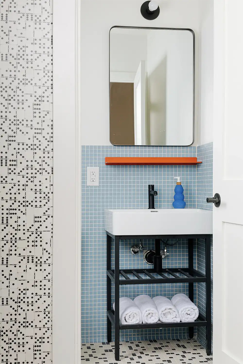 View of a blue tiled bathroom white door frame with its wall build by domino pieces