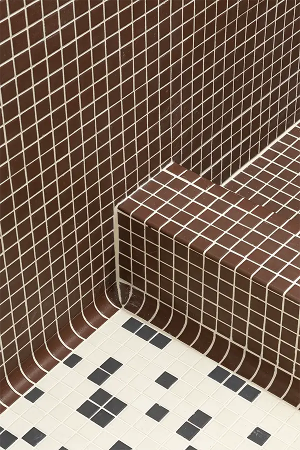 Modern bathroom design with brown mosaic shower tiles and patterned black-and-white floor tiles