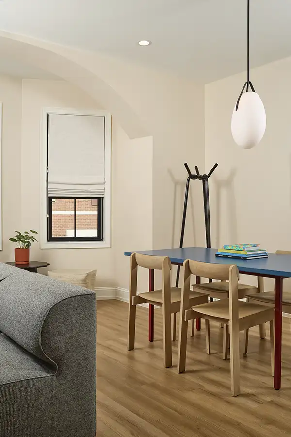 Blue wood table with 4 wood chairs around, books on top and a hanging lap