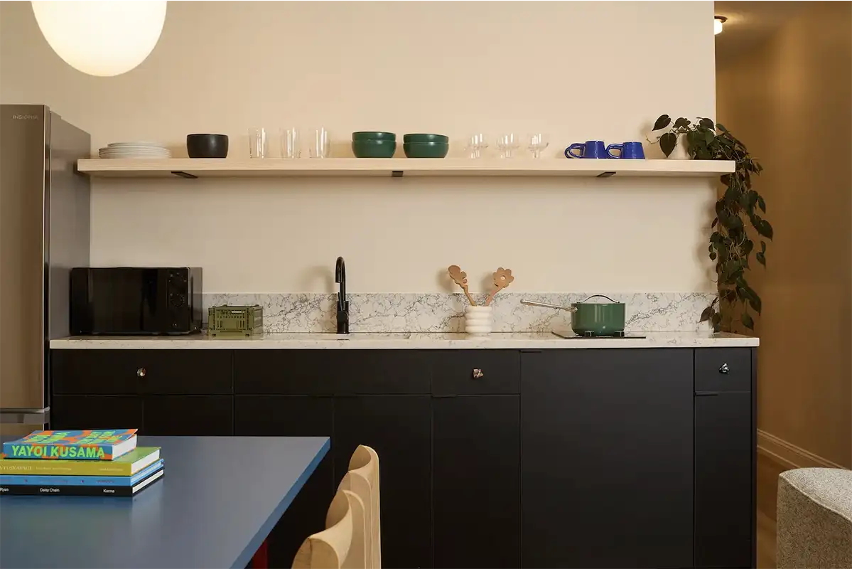 marble kitchen counter with black wood furniture underneath and kitchen utensils on top