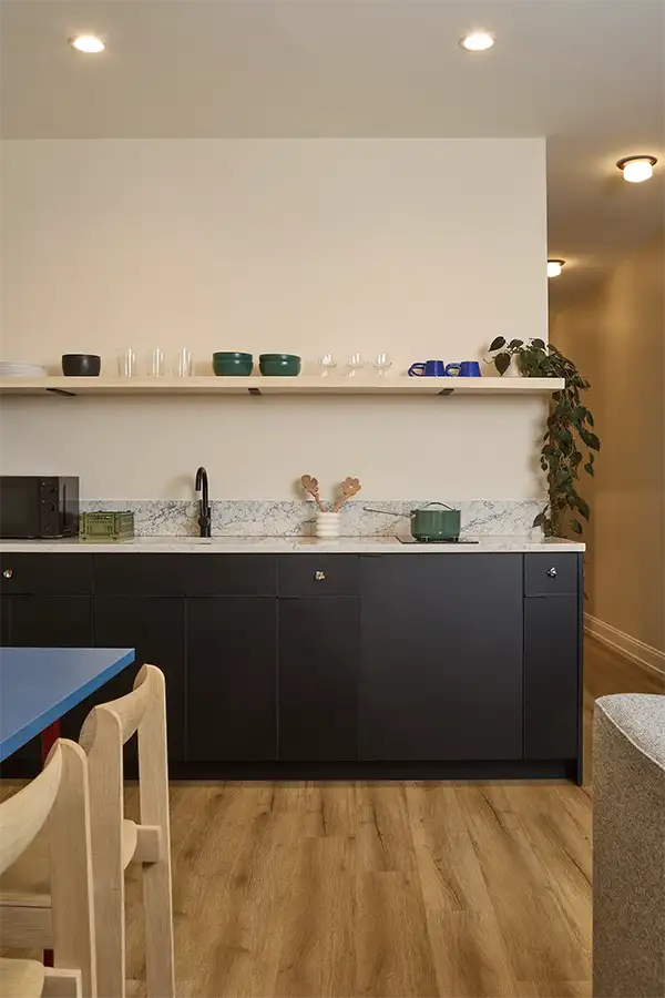 marble kitchen counter with black wood furniture underneath and kitchen utensils on top