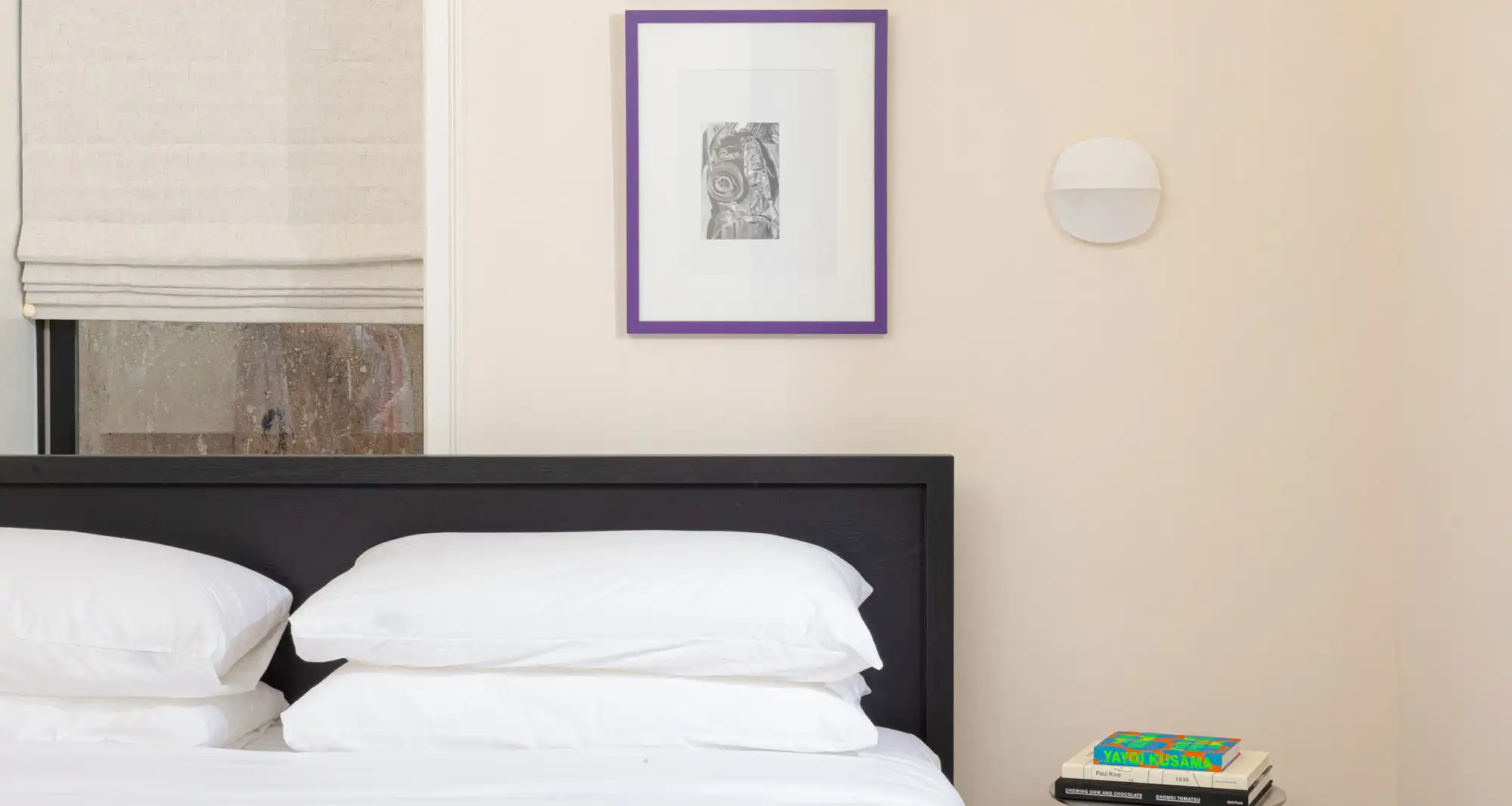 beige room, with a bed with white sheets and a purple framed picture