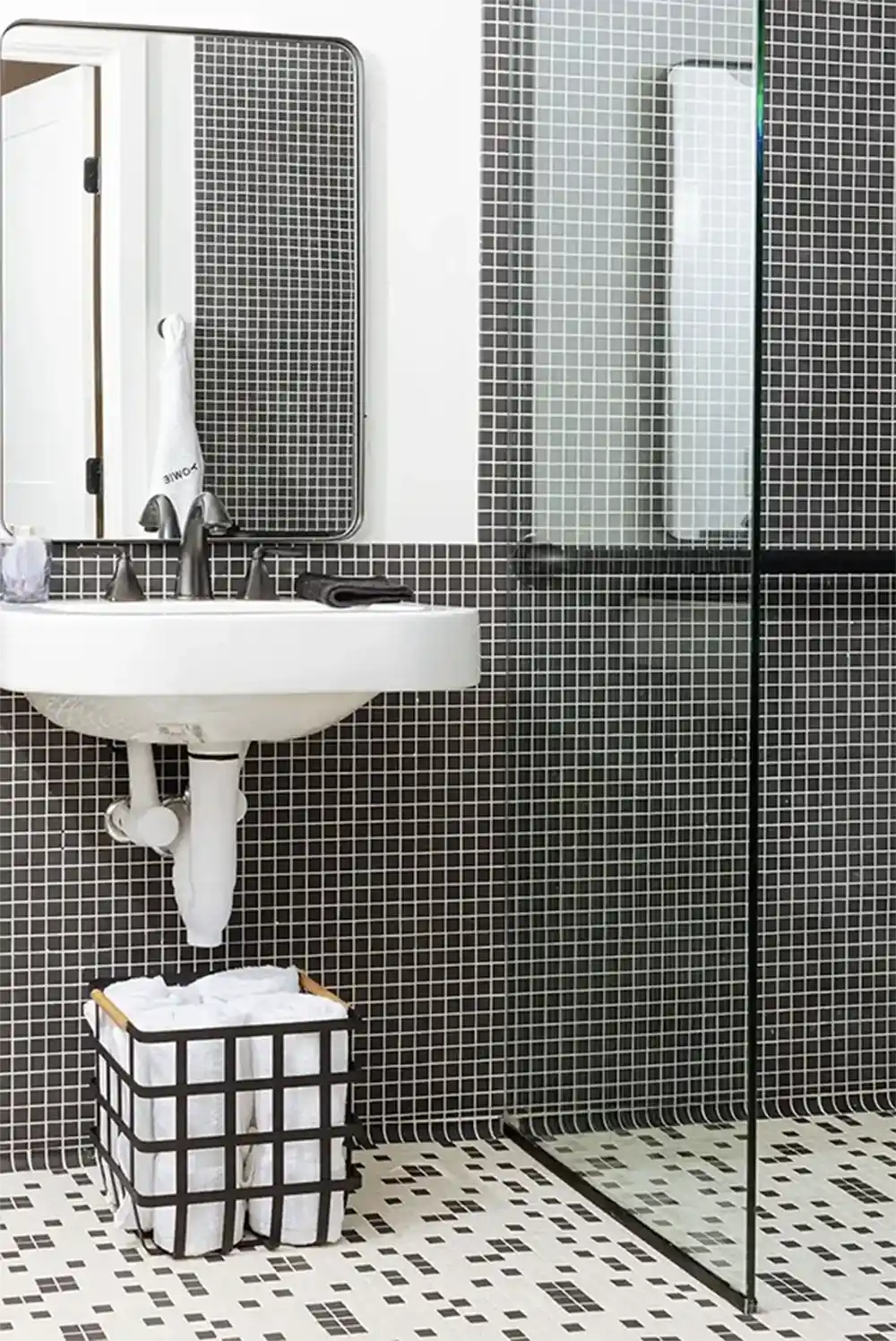 Bathroom with black tiles, withe sink and a glass bathroom division