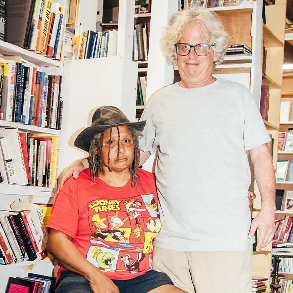 man and woman posing and smiling at the camera in the middle of a library