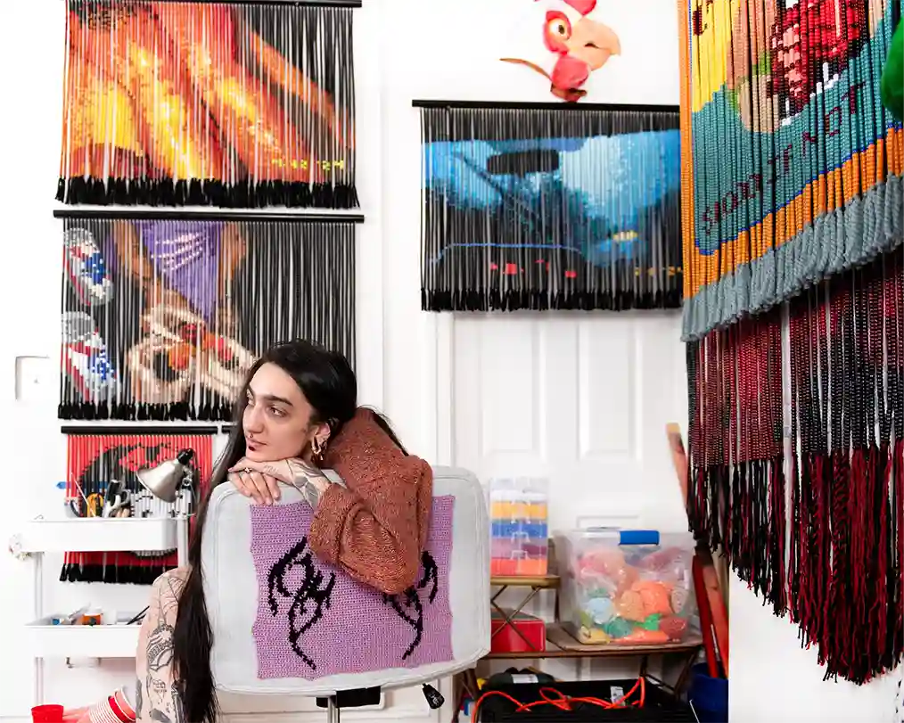 woman sitting in a room full of knitted pictures