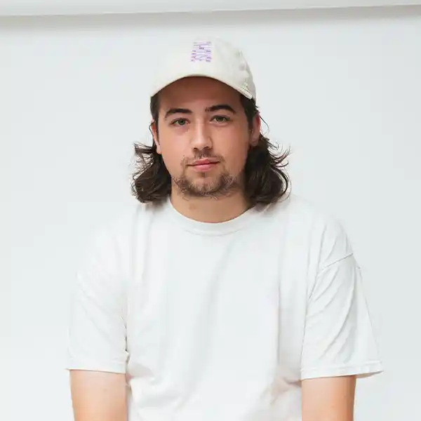 close-up of a long-haired man wearing a cap and white t-shirt