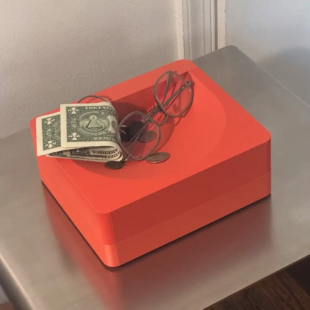 orange sculpture with some bills and glasses on top