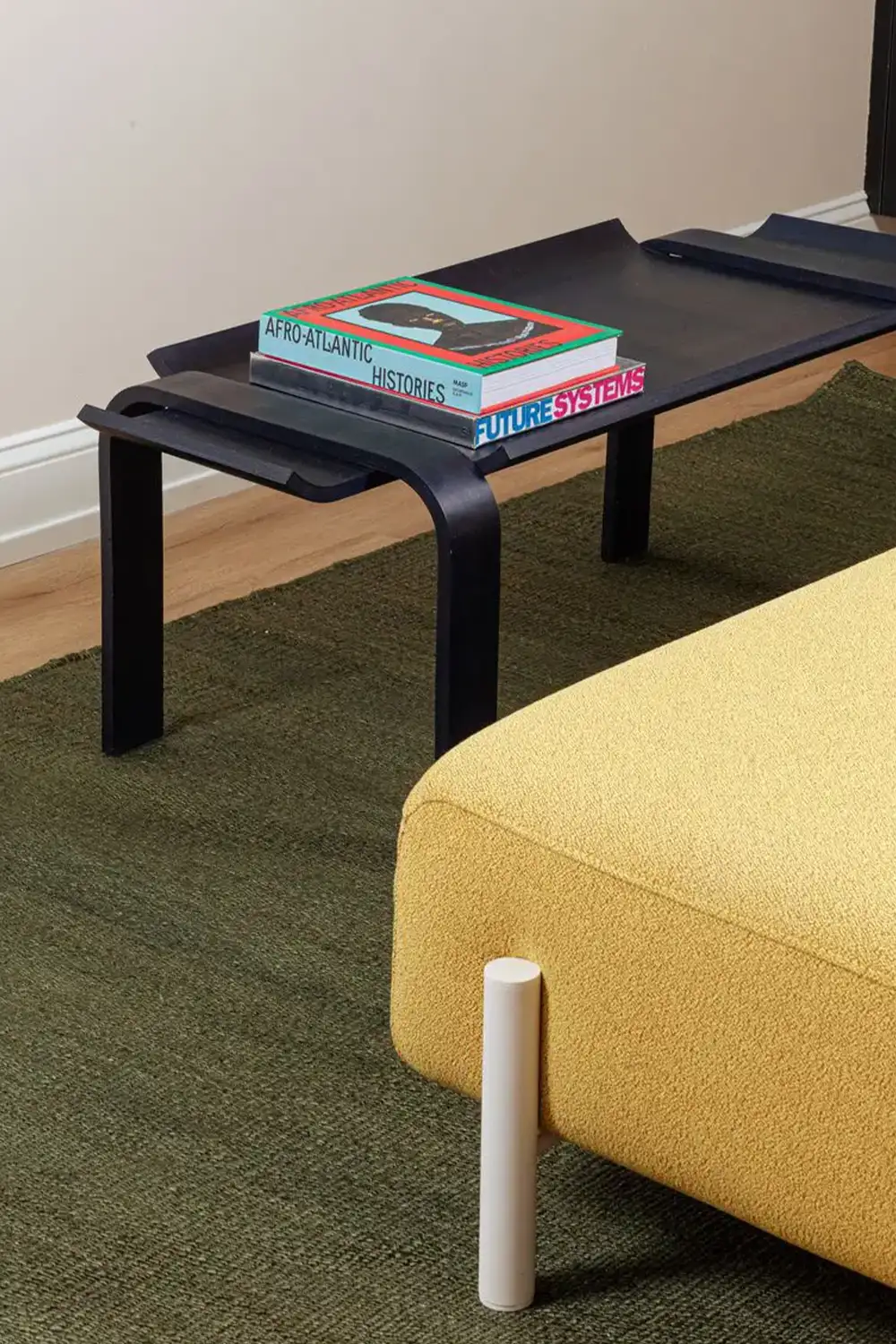 Yellow sofa next to a black table with books on it