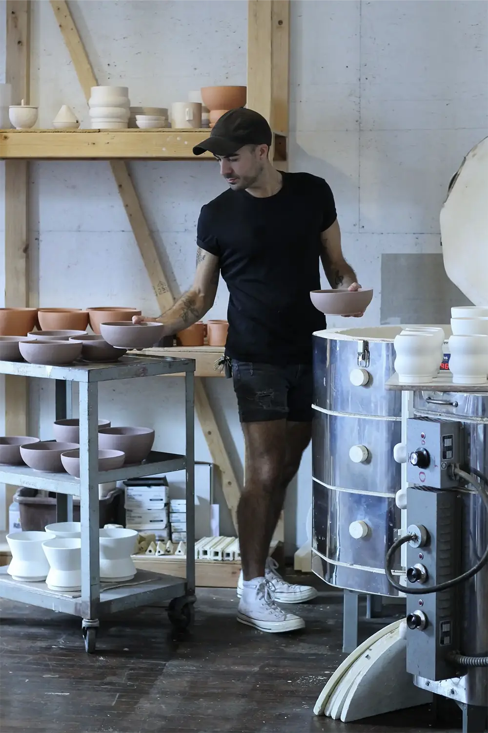 Man wearing black shorts and t-shirt taking bowls out of a clay oven