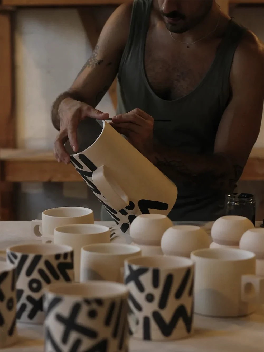 Man painting a white ceramic jug with a brush