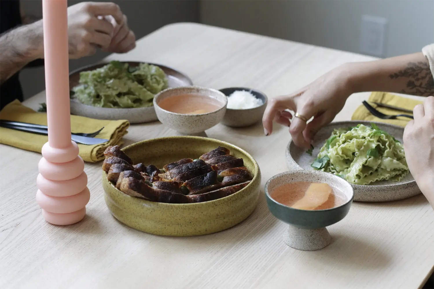 Served table with two pasta grey ceramic bowls and a bread green ceramic plate