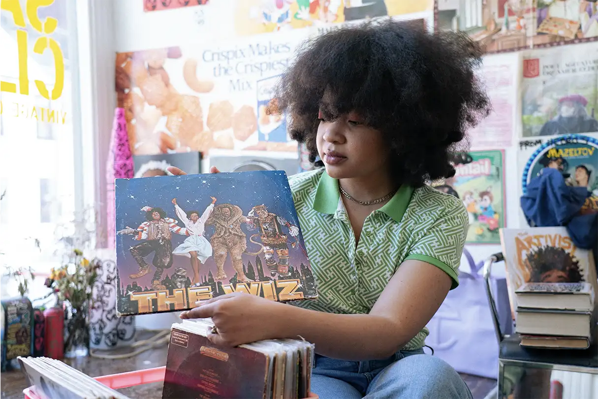 Afro young woman wearing a green t-shirt holding a vinyl record of the wiz