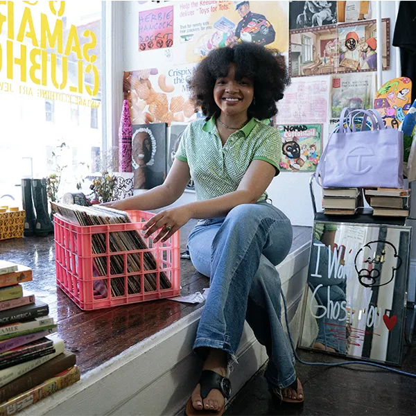 Afro young woman sitting on a platform next to a window with a basket full of