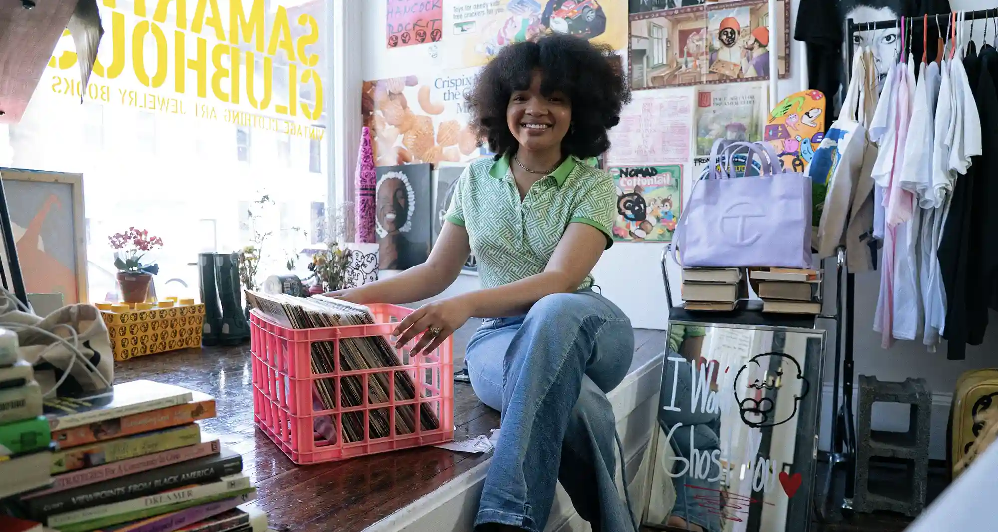 Afro young woman sitting on a platform next to a window with a basket full of vinyls