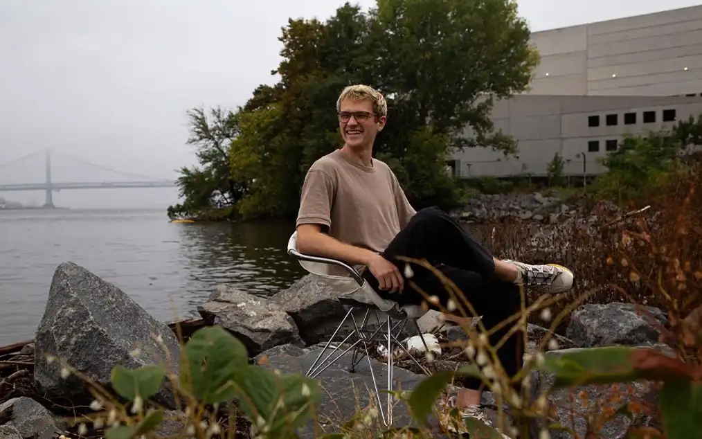 man sitting on a rock in the middle of a river