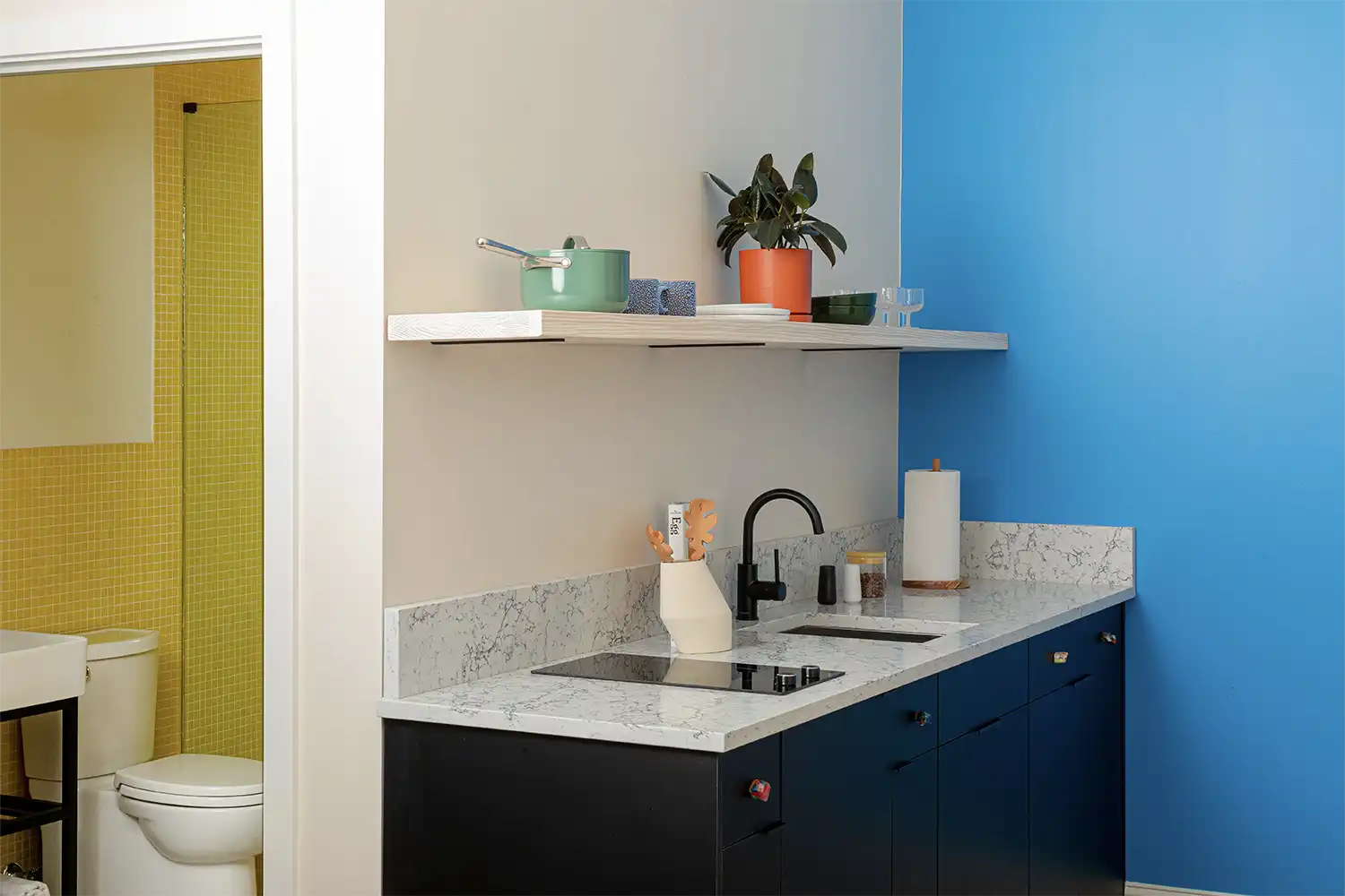 Marble kitchen counter with a blue wall and some kitchen utensils