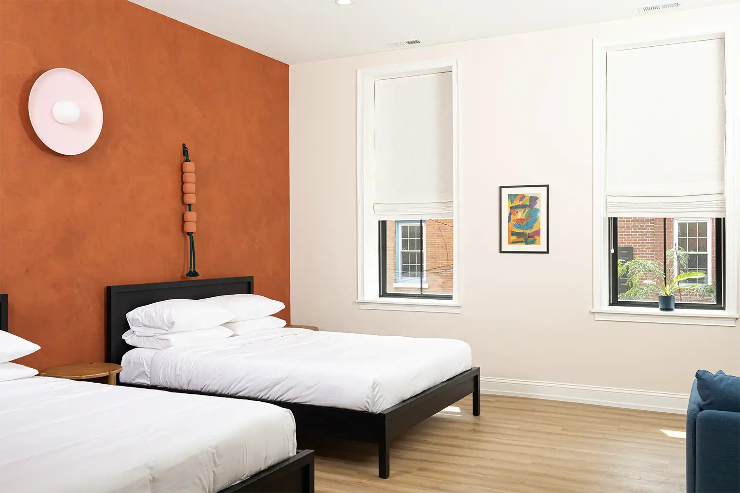 Beige and terracotta bedroom with two beds with white sheets and two windows