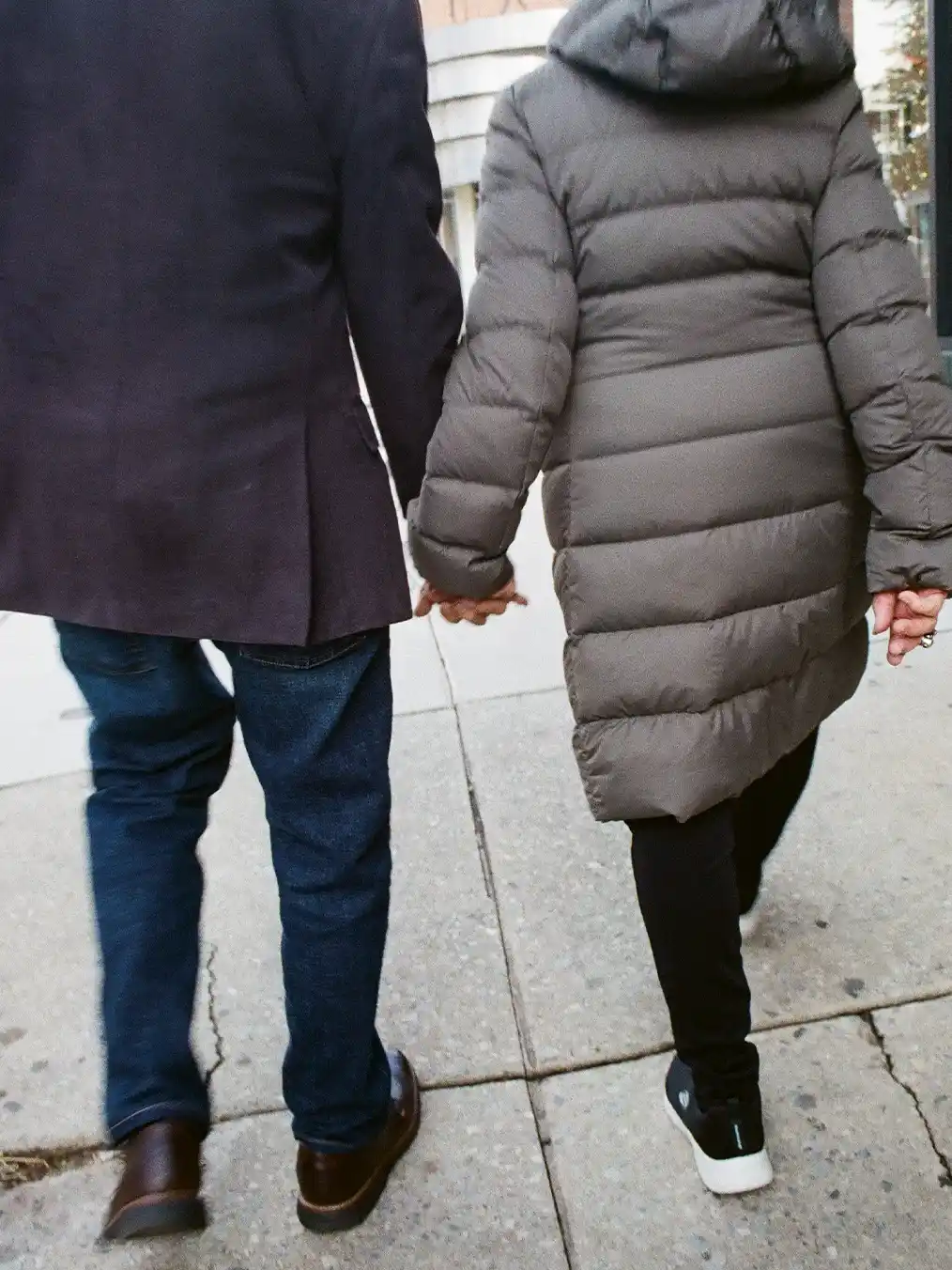 a couple with their backs turned holding hands walking