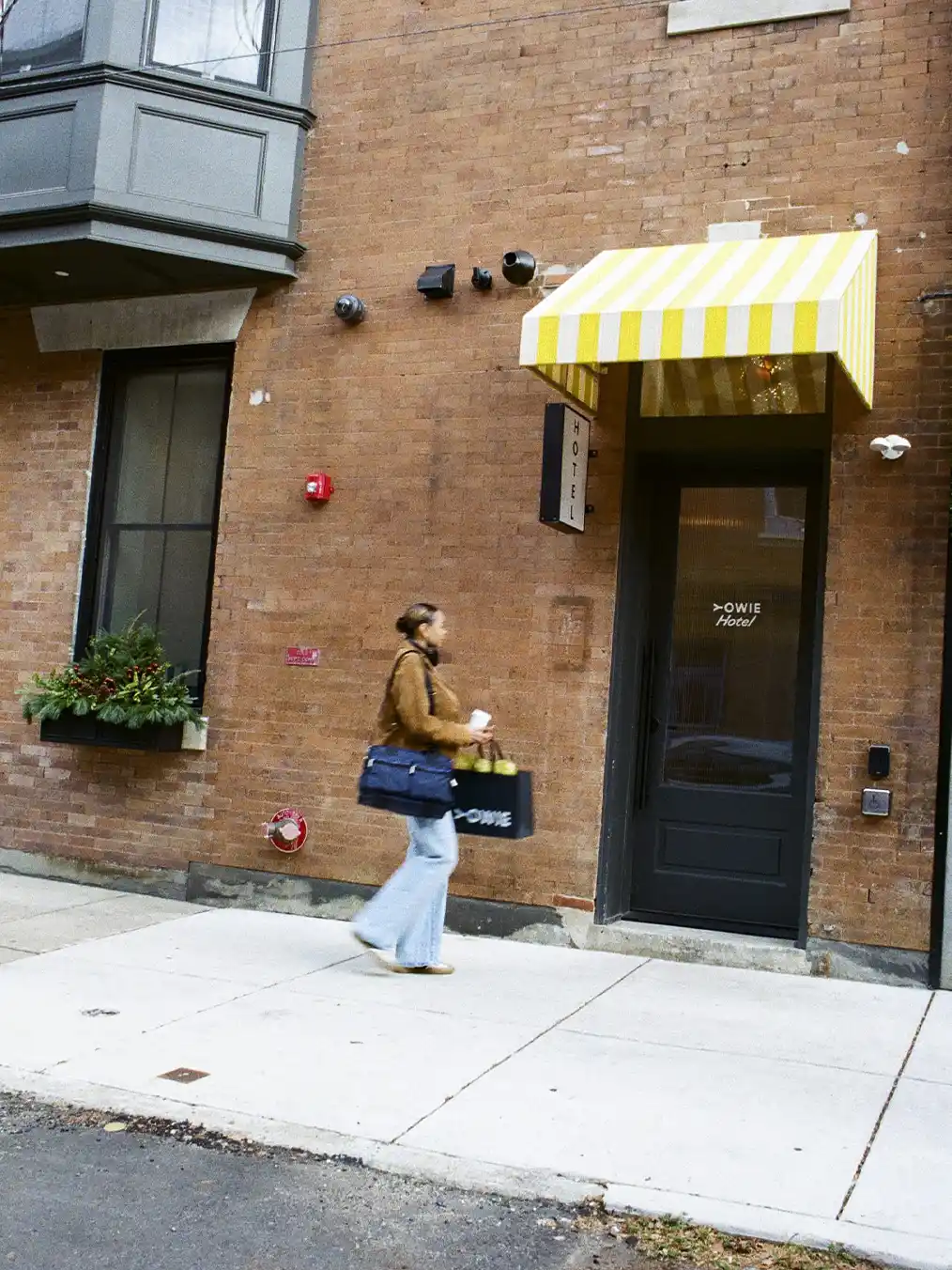 woman in a brown jacket and light jeans walking in the city