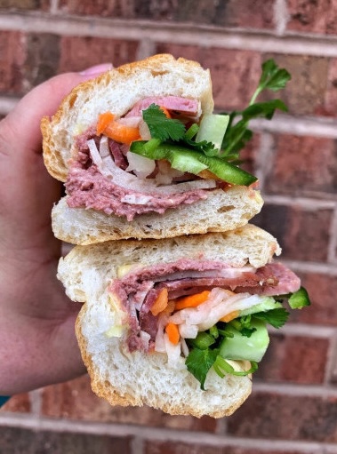 Banh mi from Café Cuong, cut in half and held up against a brick wall.