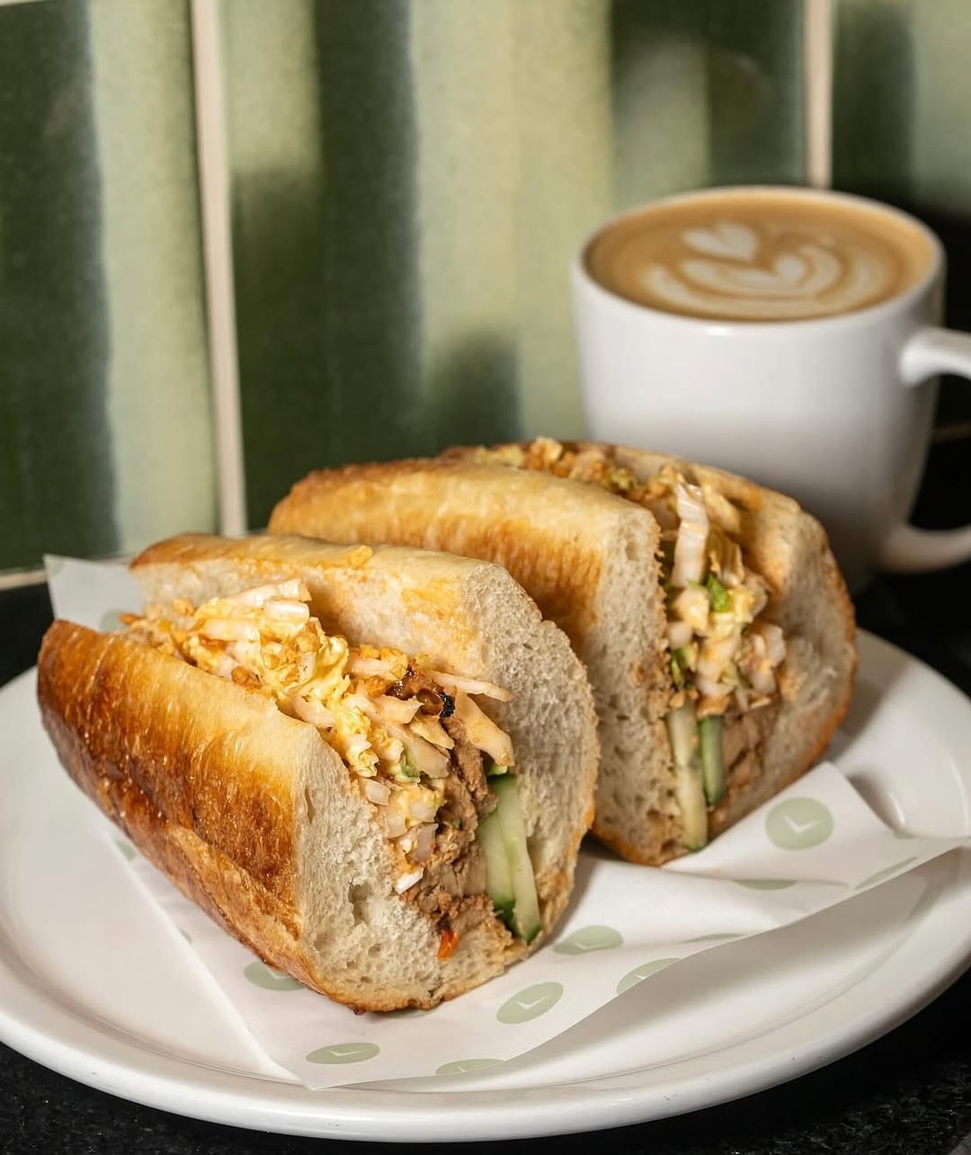 Huli Huli Chicken sandwich from Forin Café served on a plate with a latte