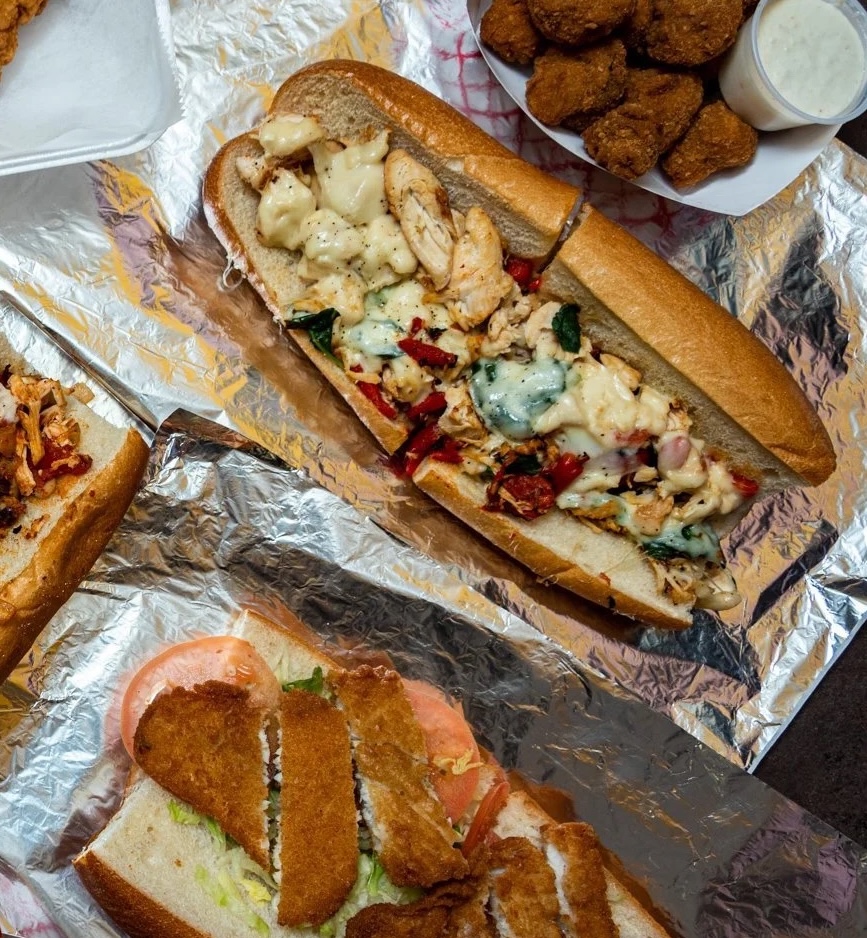 Close-up of an Ishkabibble’s chicken cheesesteak with sides.