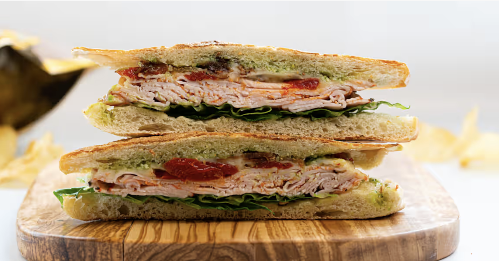 Stacked turkey panini from Palm Tree Market on a wooden board.