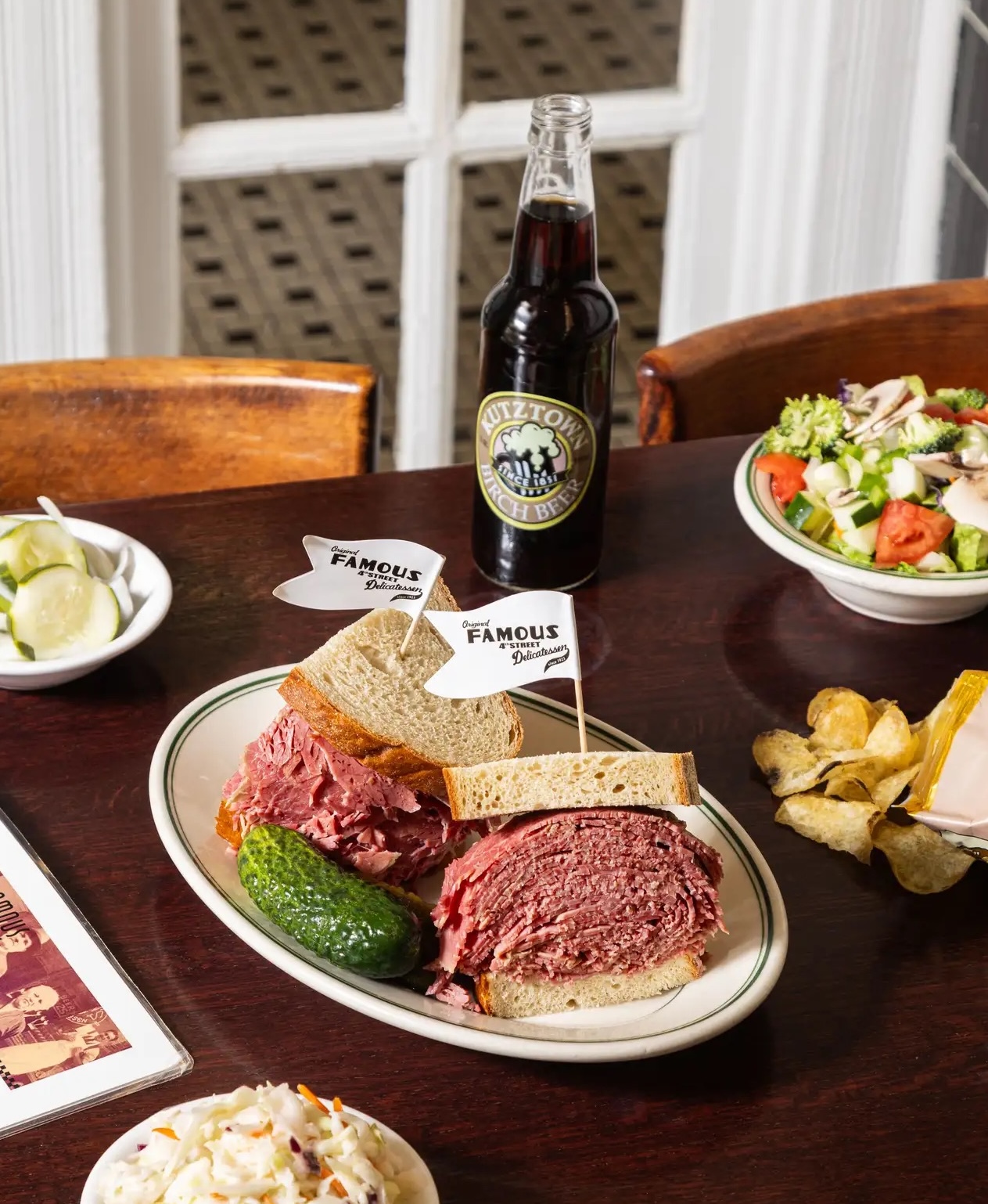 Pastrami sandwich from Famous 4th Street Deli served with a pickle on a table