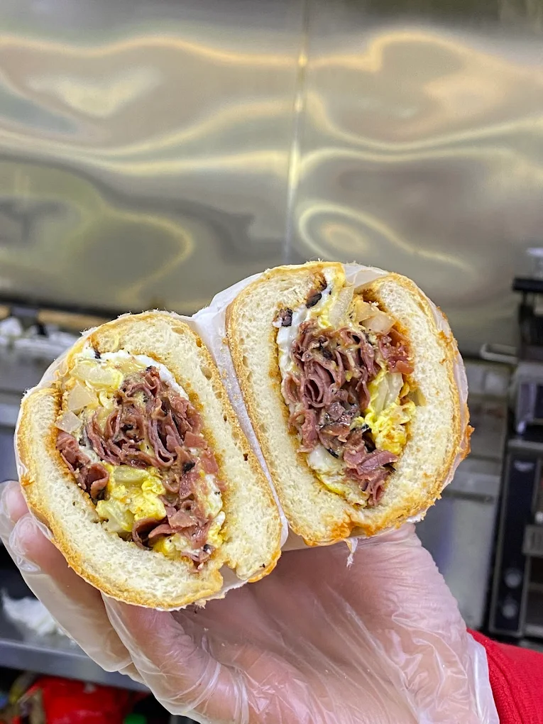 Fresh 2 Go sandwich held up in a gloved hand, shown cut in half.